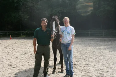 Dr. Bruce with a horse and its owner in a riding ring